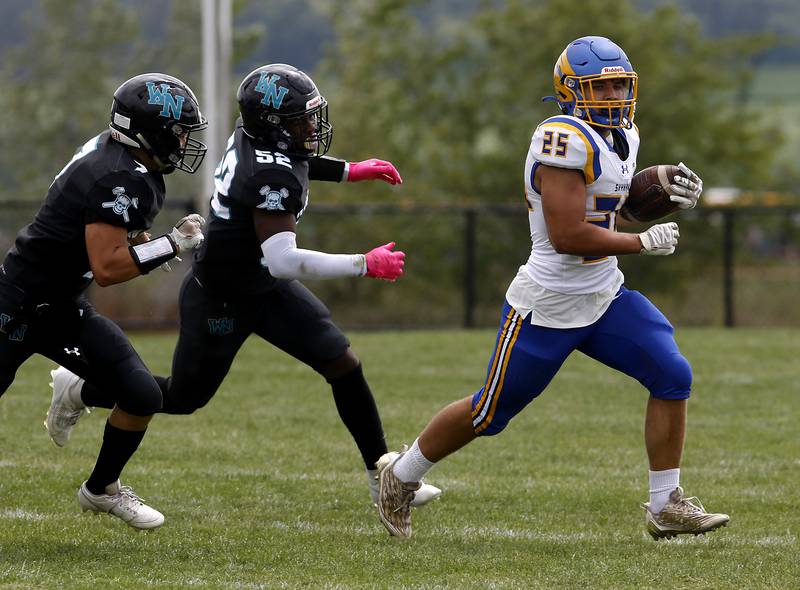 Johnsburg's Brett Centnarowicz runs away from the pursuit of \Woodstock North's George Kingos (left)  and David Randecker ball during a Kishwaukee River Conference football game against Woodstock North Saturday, Aug. 26, 2023, at Woodstock North High School.