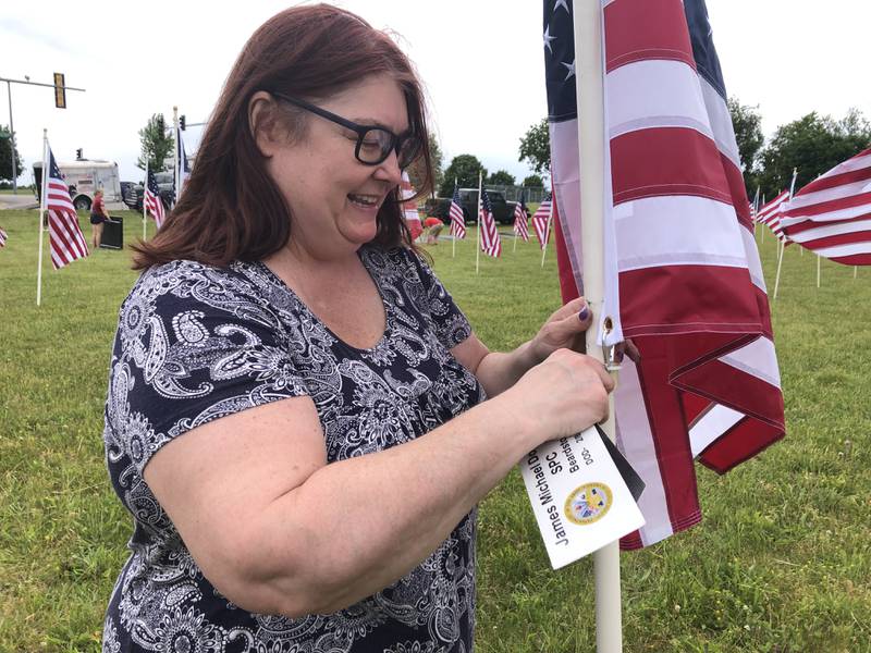 Deborah Barger helps set up the Field of the Fallen flag display in Cary on May 24, 2024, to commemorate fallen servicemen and women from Illinois during Memorial Day weekend. She tags flags with information about who each on honors.