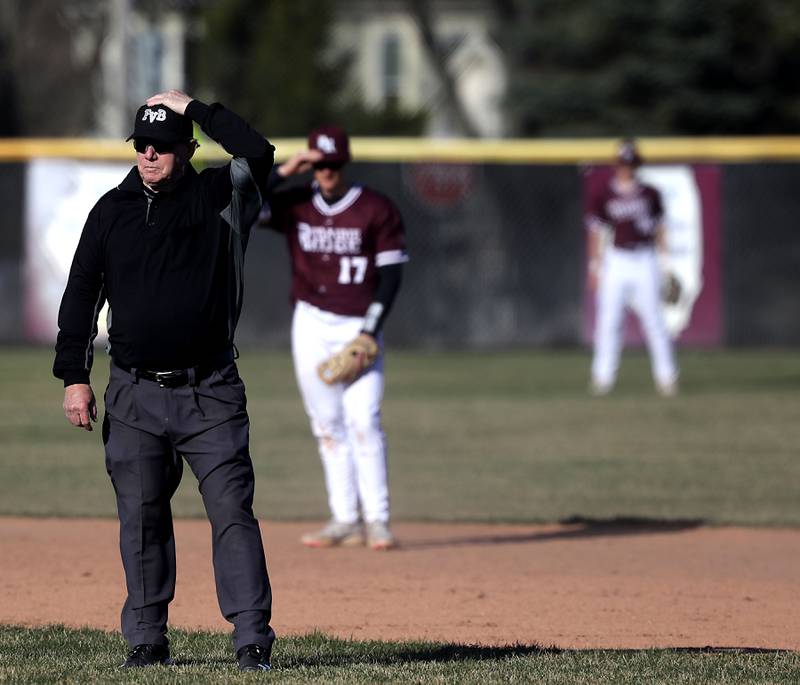 The infield umpire holds his cap as a big gust of wind blows during a Fox Valley Conference baseball game between Prairie Ridge and Cary-Grove on April 8, 2026, at Prairie Ridge High School.
