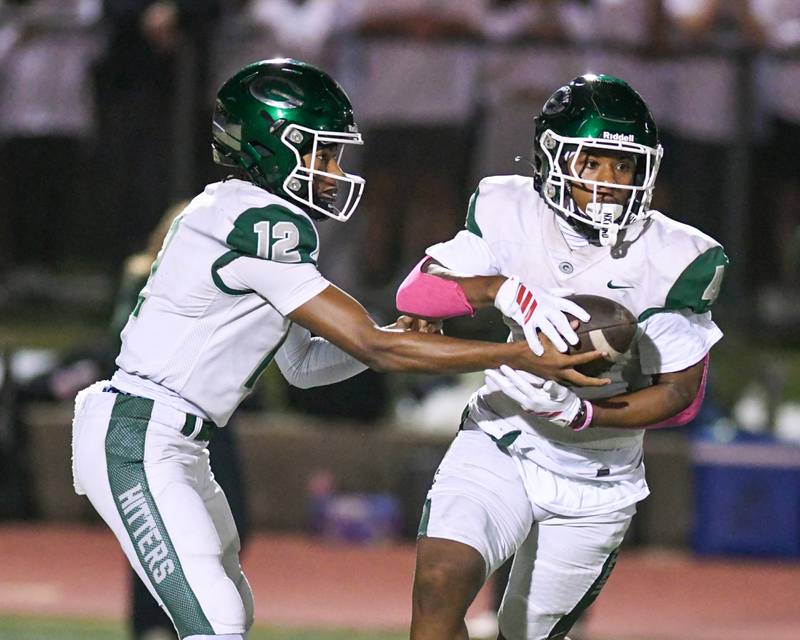 Glenbard West's AJ Rayford (12) hands the ball off to teammate Jamarcus Kelly (4) during the game on Friday Oct. 17, 2025, while traveling to take on York High School.