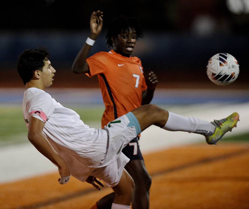York’s Jose Herrera bicycle kicks the ball to keep it in play as Romeoville’s Christian Agyekum watches in the Class 3A semifinal game of the boys state soccer tournament in Hoffman Estates on Friday, November, 4, 2022.
