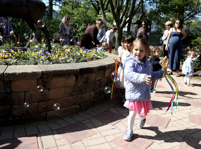 Scarlett Bailey, 4, of Glen Ellyn chases a bubble while waving her ribbons and bells during a childrens’ storytime as part of Lilac Time at Lilacia Park in Lombard.