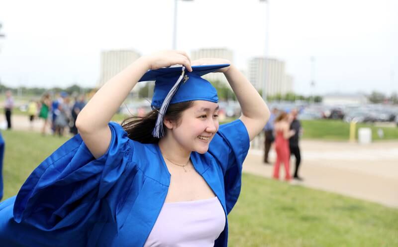 Geneva High School graduate Jeanine Hellstrom holds her cap in the wind outside the Northern Illinois University Convocation Center in DeKalb before the school’s 2022 Commencement Ceremony on Tuesday, May 31, 2022.