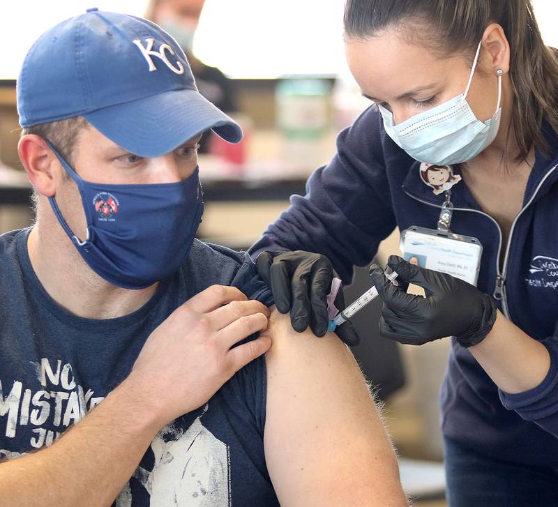 Travis Karr, a City of DeKalb firefighter/paramedic, receives an injection of the Moderna COVID-19 vaccine from DeKalb County Health Department public health nurse Alex Diehl Thursday in DeKalb.