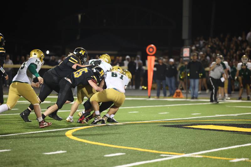 Herscher's Nash Brubaker and Jaxon Sukley push teammate Alek Draper forward toward a first down as Bishop McNamara defenders, including Kian Bramer (67) make the tackle during the Fightin' Irish's 45-28 victory over the Tigers on Friday, Sept. 5, 2025.