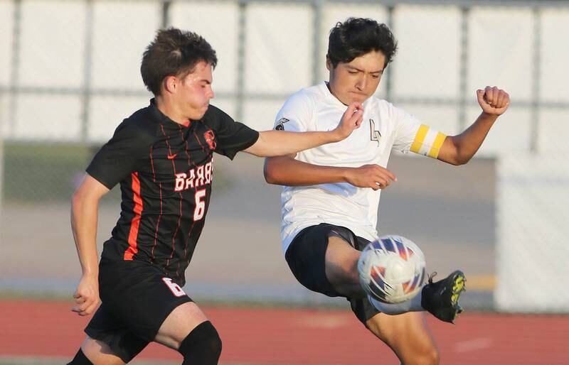 Sycamore's Willie Romero (right) kicks the ball by DeKalb's Landon Weishaar during their game Tuesday, Oct. 4, 2022, at DeKalb High School.