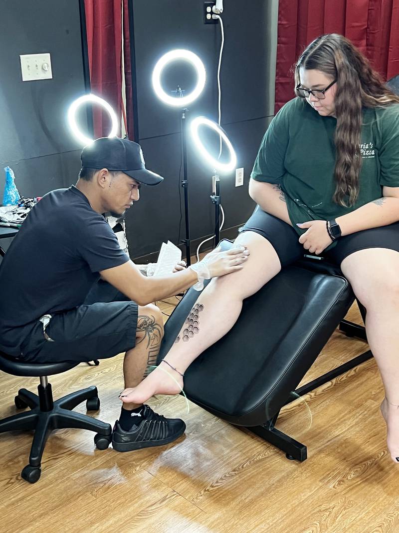 C/S Tattoo Shop owner Carlos Silva works on a custom tattoo for customer Alex Barajas.