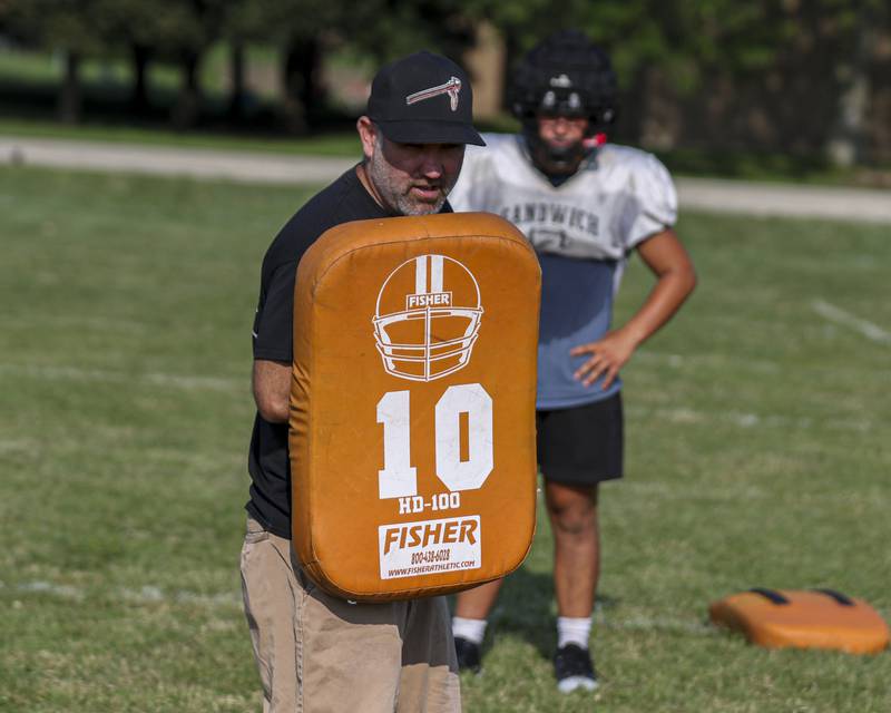 Head coach Jason VanPelt instructs the team proper blocking techniques during Sandwich football practice Tuesday, July 22, 2025 in Sandwich.