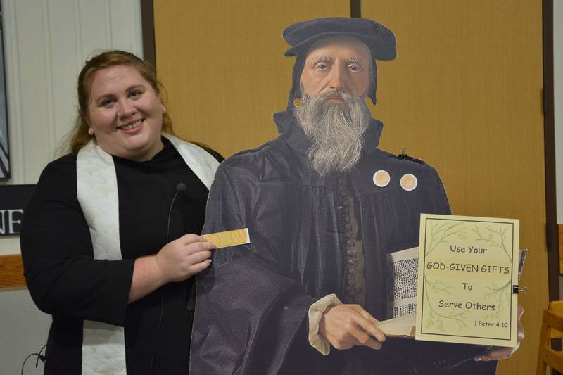 Pictured: Associate Pastor Molly Morris placing a bandage on a cutout of John Calvin, a Presbyterian Church founder. The church's congregation plans on covering the cutout with bandages as they work to raise their $10,000 goal.