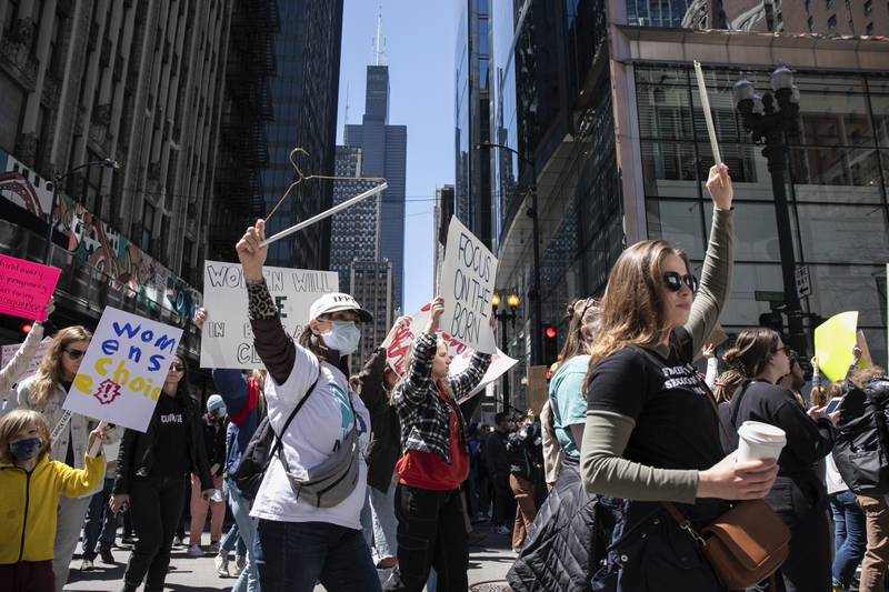 An abortion-rights activist holds a hanger during a rally along North State Street in the Loop, Saturday, May 7, 2022, in Chicago. Thousands attended the rally, which was organized in response to a leaked Supreme Court draft opinion written by Justice Samuel Alito, who supported overturning Roe v. Wade. If overturned, abortion would become illegal in 26 states. | Pat Nabong/Sun-Times/Chicago Sun-Times via AP)