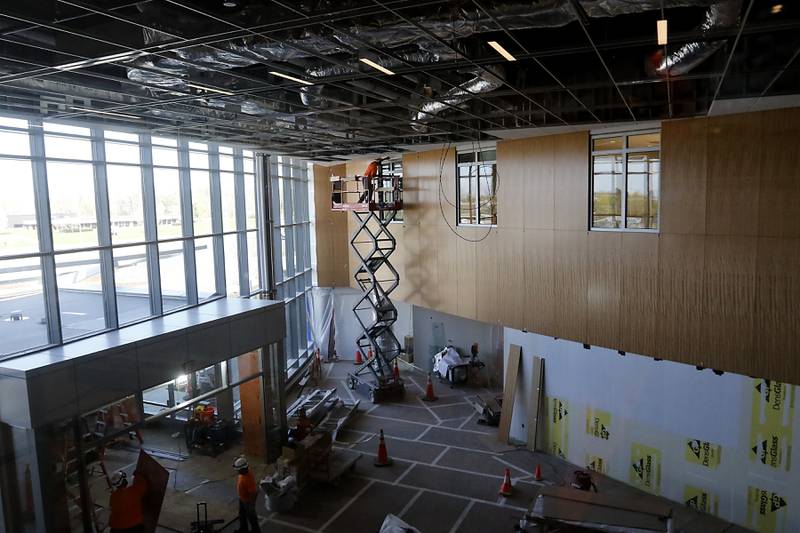 A construction worker installs paneling in the lobby on Friday, April 21, 2023, as construction continues on the new Mercyhealth hospital in Crystal Lake. The hospital is ramping up hiring as it gets set to open in this summer.