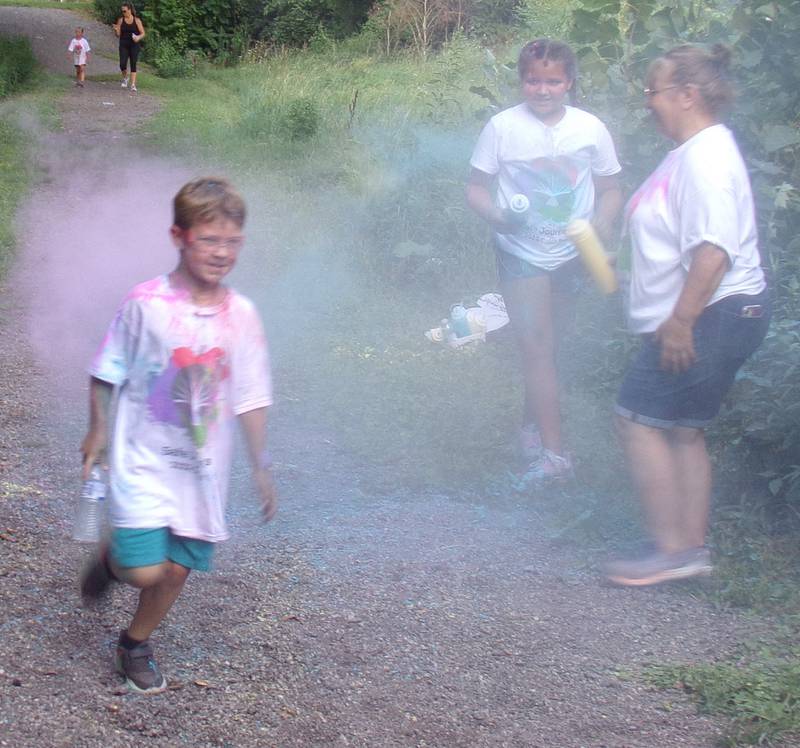 A young runner emerges from a powder cloud of color at the finish line of the Safe Journeys Color Run on Saturday, Aug. 6, 2022, at Twister Hill Park in Streator.