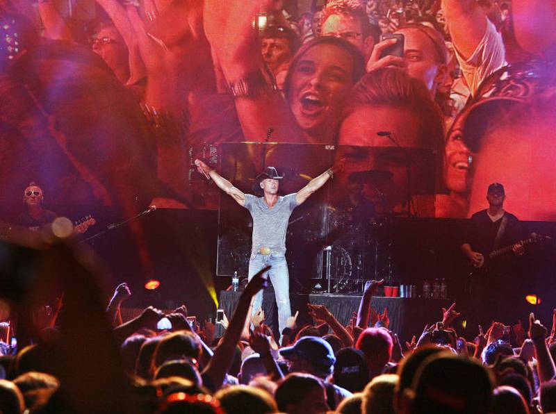 Backed by a large video screen image showing the crowd in front of him, country music star Tim McGraw raises his arms during a Saturday night show at Illinois Valley Regional Airport in Peru. Proceeds from the Concerts For A Cause show will benefit the March of Dimes.