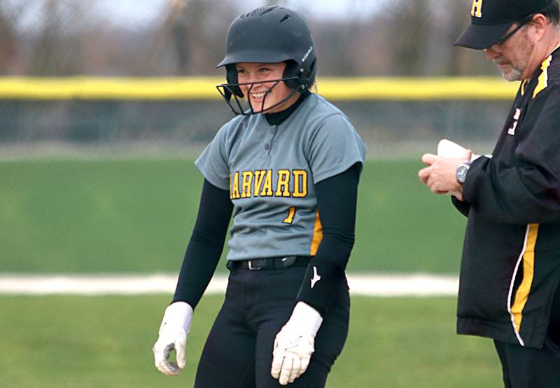 Harvard’s Tallulah Eichholz grins as she arrives at first base with a single in varsity softball at Marengo Thursday.