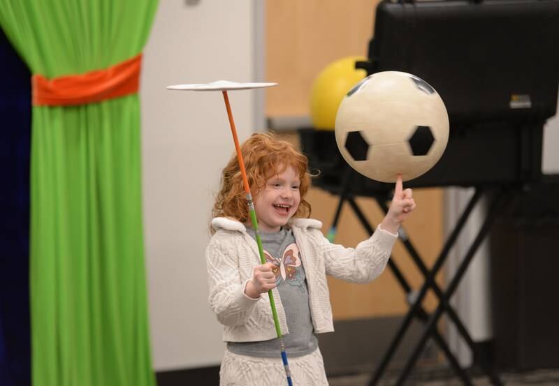 Helena Cerovac of Glen Ellyn demonstrates how to juggle with the help of Jason Kollum during the See a Juggler, Be a Juggler held at the Glen Ellyn Library Saturday April 5, 2025.