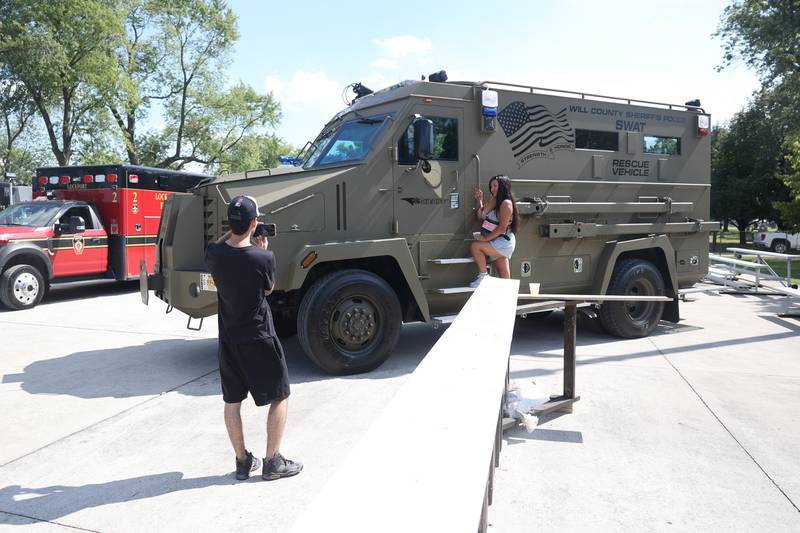Wilson David takes a photo of Sorel Flores on the Will County Sheriff’s SWAT Rescue Vehicle at the Crest Hill Lions Luau and Car Show on Sunday, Sept. 1, 2024 in Crest Hill.