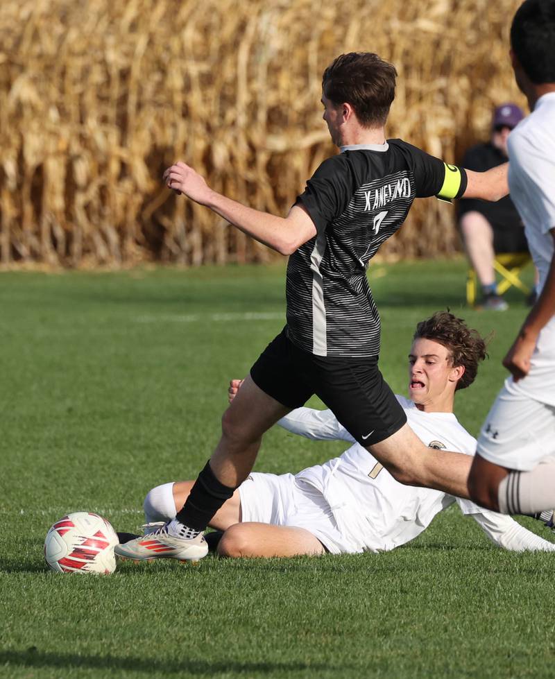 Sycamore's Noah Daykin slides to try to kick the ball away from Kaneland's Cameron Guernon during their game Monday, Oct. 7, 2024, at Kaneland High School in Maple Park.