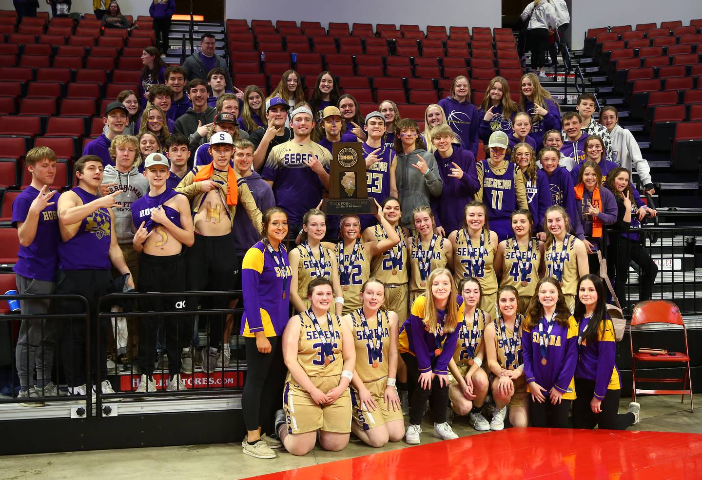 The Lady Huskers girls basketball team celebrates with their fourth-place trophy Thursday, March 3, 2022, at Redbird Arena in Normal.