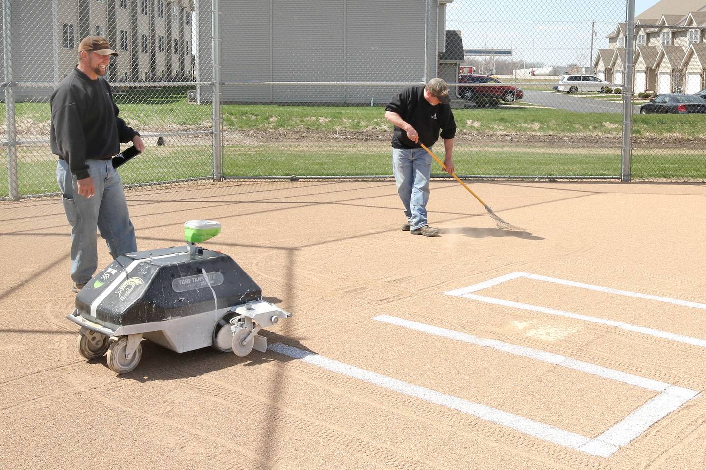 Nik Vinz, (left) and Dane Shaw, both maintenance for Sycamore Community School District 427, get the softball field ready for a game Tuesday, April 11, 2023, at Sycamore High School.