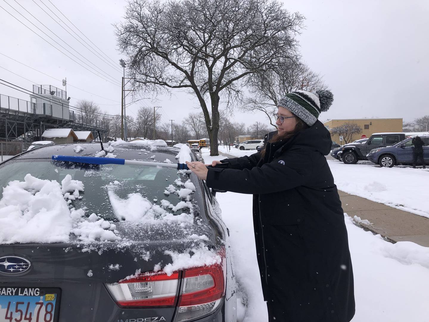 Kim Lowrey shovels snow off her car March 22, 2024 in McHenry.