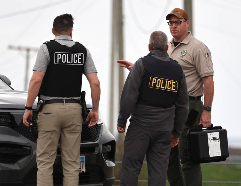 Law enforcement officials talk near a Honda sedan with a shattered window in the westbound lanes of Interstate 88 Monday, April 27, 2026, as they investigate an incident on I-88 just west of Keslinger Road in Maple Park.
