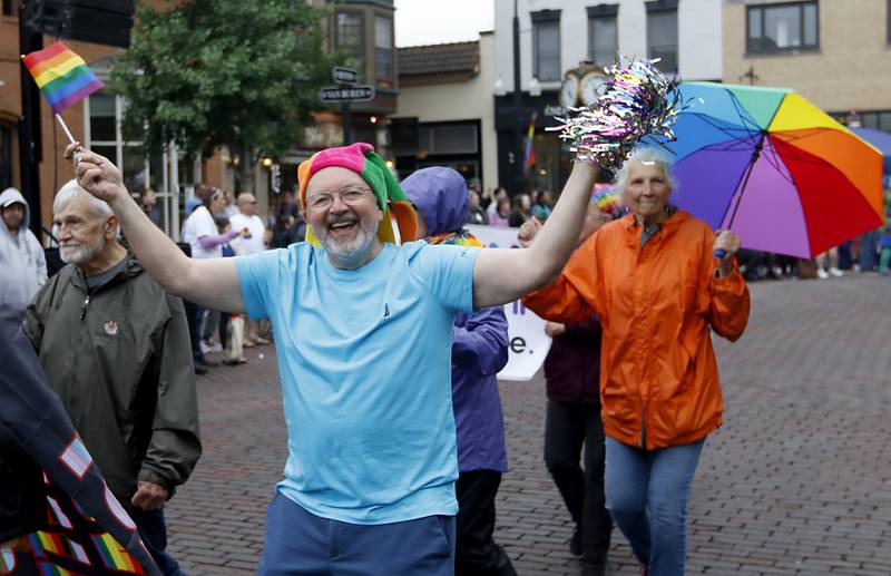 Ron Relic wages a flag and cheered as he marches with the Tree of Life Unitarian Universalist Congregation in the Woodstock PrideFest Parade Sunday, June 11, 2023, around the historic Woodstock Square.