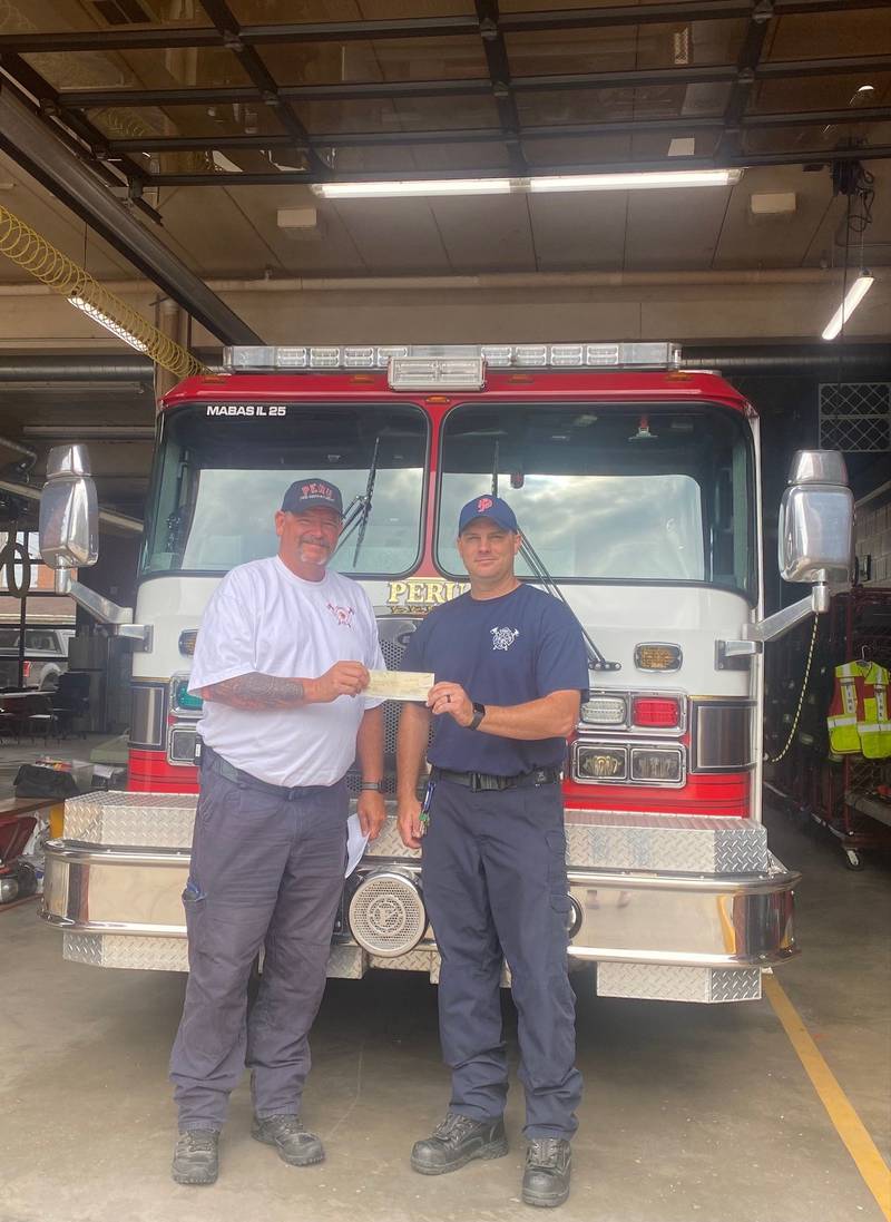 Peru Fire Chief Jeff King holds $1,000 donation with Engineer Captain Bill Krolak from Catholic War Veterans Post 1229.