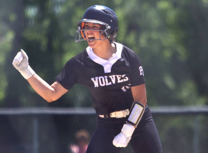 Prairie Ridge’s Emily Harlow celebrates after pulling into third base with a triple against Harvard during Class 3A softball regional final action at Lions Park in Harvard Saturday.