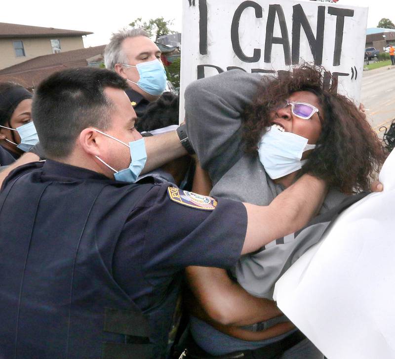 Police wrestle with protesters after they refused to clear the street Monday on Lincoln Highway in front of the DeKalb Police Department Monday during a protest that drew about 200 people who were angry about police violence and the recent death of George Floyd.