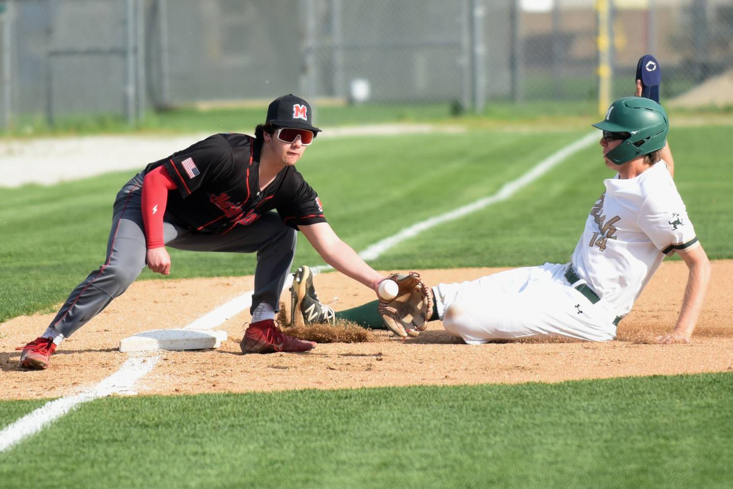 Marian Central's TJ Cutrona, left, fields a throw at third base as Bishop McNamara's Callaghan O'Connor beats the throw for a stolen base during a game at Bishop McNamara Friday, April 17, 2026.