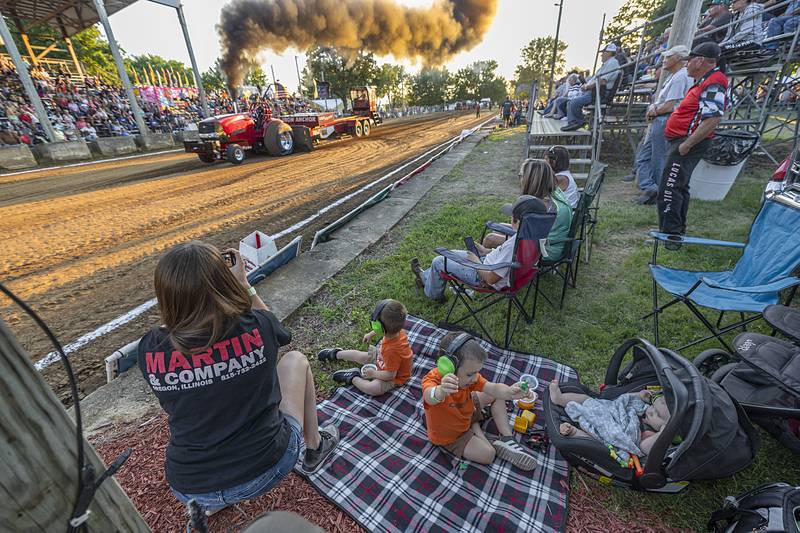 The Heeren family, Nikki, Hank, Hunter and Harvey, watch Jordan tear down the track in the Red Express on Wednesday, Aug. 7, 2024, at the Carroll County Fair’s tractor pull in Milledgeville.