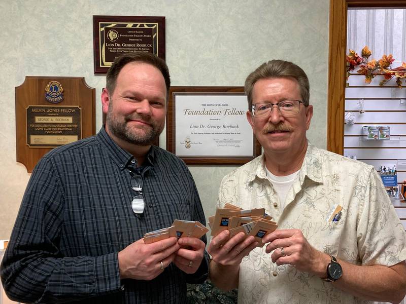 Morris Lions Club provides We Care with $5000 dollars of Aldi Foods gift cards to fight hunger over the holidays.  Pictured is Eric Fisher (left) from We Care receiving the gift cards from Lions member Dr. George Roebuck.