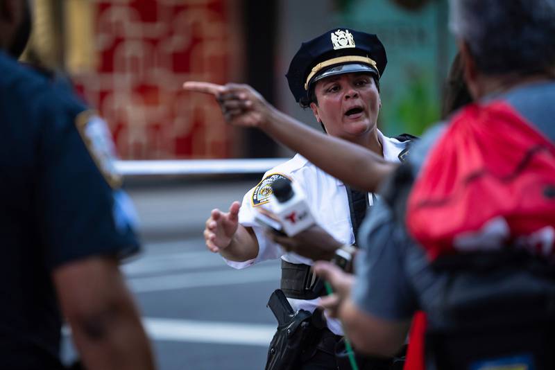 A New York police officer directs bystanders and members of the media outside a Manhattan office building where two people were shot, including a police officer, Monday, July 28, 2025, in New York. (AP Photo/Angelina Katsanis)