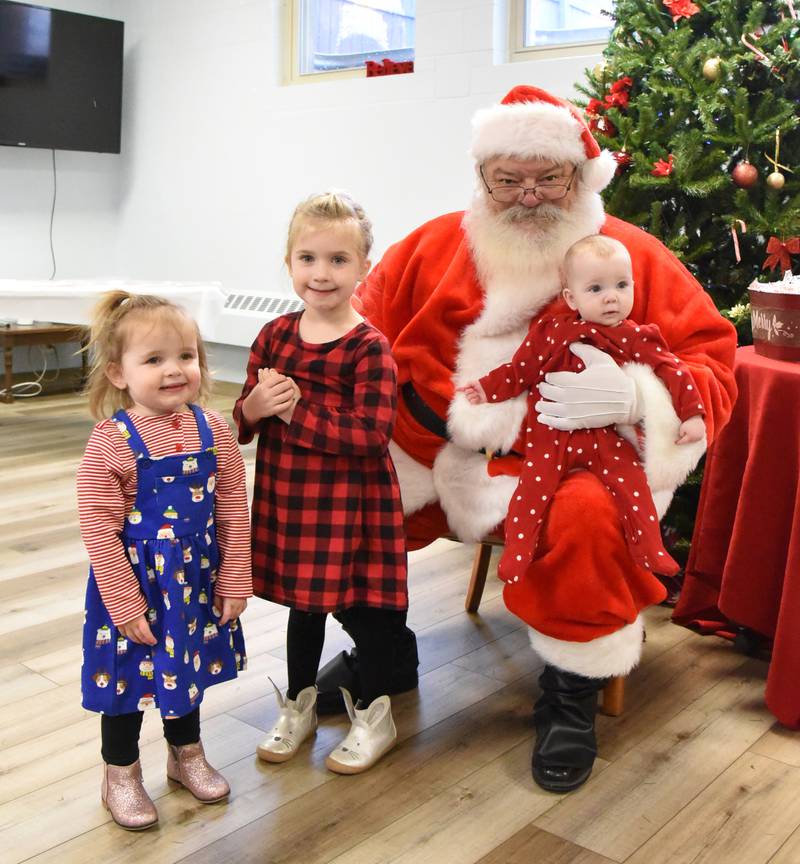 Anistyn, Ainsley, and Austyn Thomas pose with Santa at the Breakfast with Santa held during Christmas in the Village in Mt. Morris on Saturday, Dec. 2, 2023.