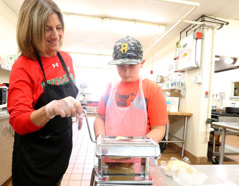 Lori Turczyn, foods instructor, helps Liam Jones crank dough through a pasta maker machine during the Area Career Center Hands-On Showcase on Thursday, June 8, 2023 at La Salle-Peru Township High School.