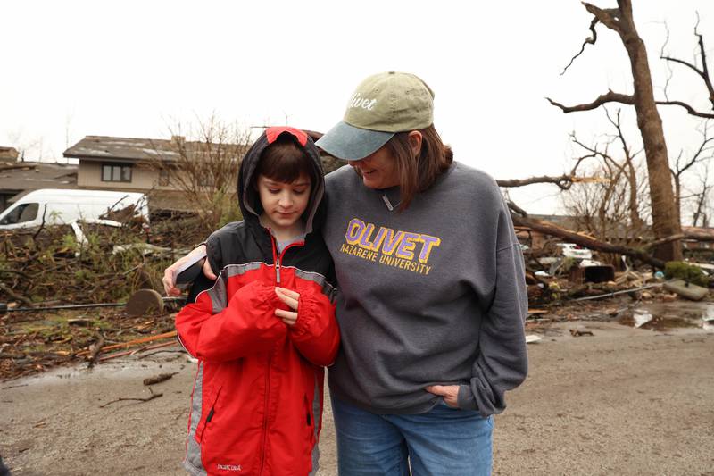 Debbie Rattin, right, of Martinton, comforts her grandson, Johnny Ascher, as they walk around his neighborhood in Aroma Township on Wednesday, March 11, 2026, following the March 10 tornado in Kankakee County. The Aschers were on the phone with Debbie and Scott Rattin as the tornado passed overhead. "We were just praying," Scott said.