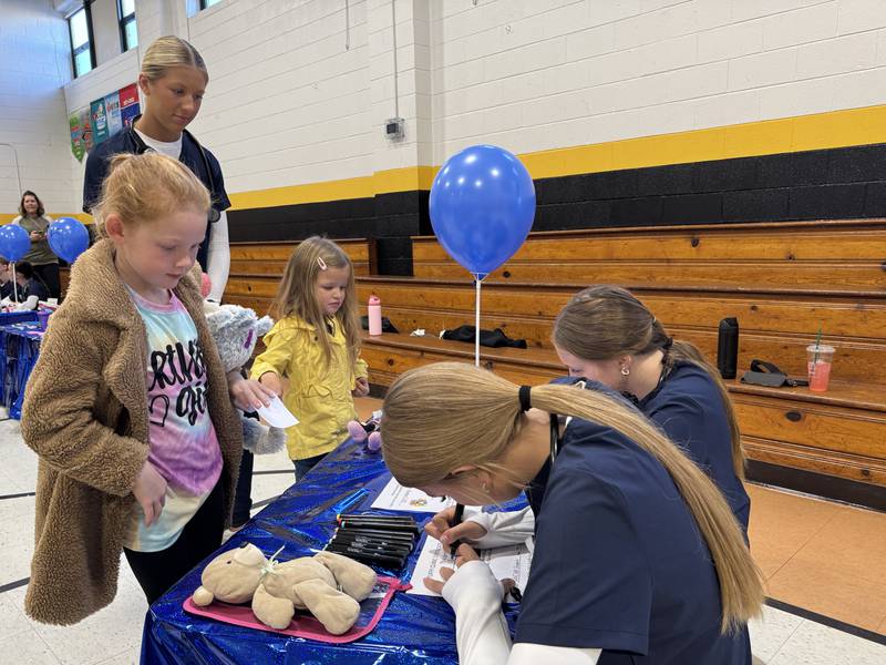 Grundy Area Vocational Center students help a Nettle Creek Elementary student fill out a form letting them know their stuffed animal has received a clean bill of health.