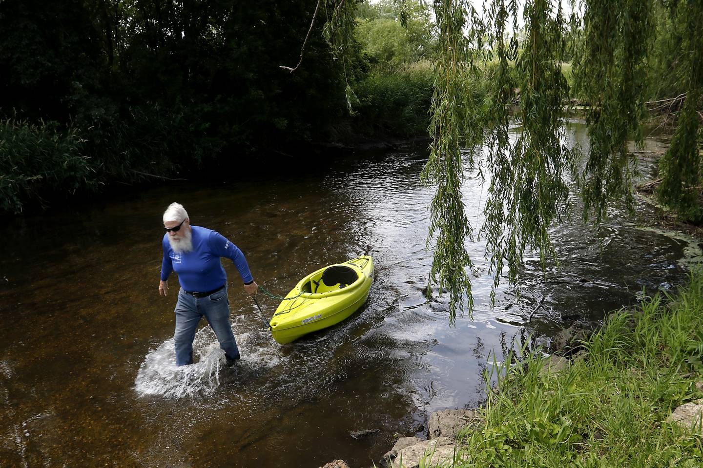 Gary Thrall pulls a kayak through a shallow section of the Kishwaukee River on Monday, June 17, 2024, at Siems Memorial Park near Union. Members of the Paddle the Kish group have finished clearing the Kishwaukee River between the Union and Marengo area so it can be paddled in kayaks.