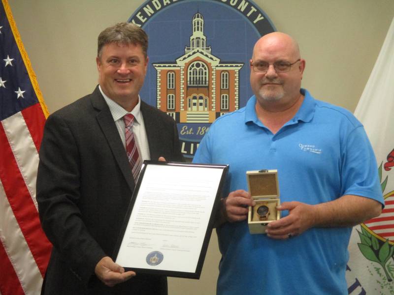 Kendall County Board Chairman Matt Kellogg, left, presents a plaque and a wristwatch to Boulder Hill resident Rob DeLong as the first-ever Kendall County Citizen of the Year.