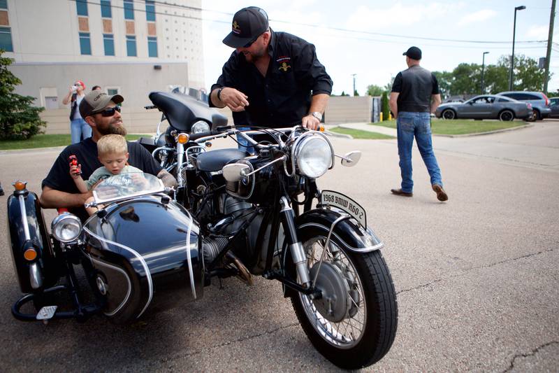 Sycamore boy Oilver Olinger, 2, and Dad Nathan Olinger, get a ride in a sidecar with Andy Koczwara outside Sycamore Public Library Sunday, June 22, 2025. More than 100 bikers plus law enforcement escorted Olinger to the St. Charles Motorcycle Museum to celebrate the boy's cancer remission.