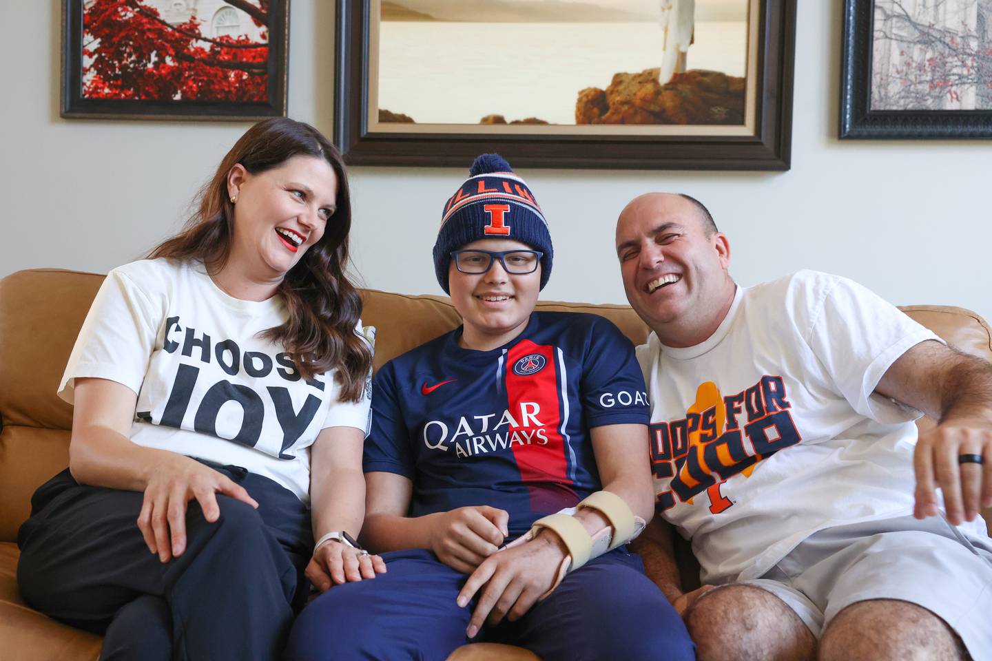 Cooper Freedlund, 13, center, sits with his parents, Jamie, left, and Gary Freedlund, at their Bourbonnais home on July 3, 2025. The Freedlunds, who run Mattea's Joy, a nonprofit that supports families with hospitalized children which they started in honor of their late daughter, Mattea, spoke on the experience of navigating Cooper's cancer diagnosis and treatment.