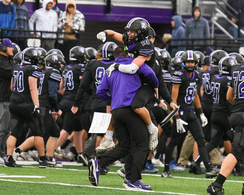 Downers Grove North's Oliver Thulin (10) celebrates with a member of the coaching staff after winning the second week class 7A game over Fenwick from a field goal in the last seconds of the game on Saturday Nov. 9, 2024, held at Downers Grove North High School.