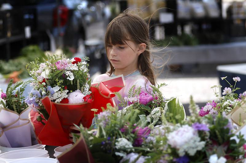 Hazel Stewart, 9, of Crystal Lake picks out a bouquet of flowers from the Piscasaw Gardens booth Tuesday, June 20, 2023, at a Summer Woodstock Farmers Market around the Historic Woodstock Square. People were able to shop from over 40 of their favorite farms & producers for in-season food fresh produce, dairy, meats, breads, baked goods, spices, herbs, pasta, flowers and more.