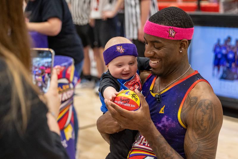 Kamil “Dragon” Brown (77) of the Harlem Wizards takes photo with child on Wednesday, April 16, 2025 at Woodland High School in Streator.
