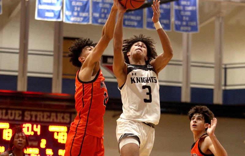 McHenry’s Adam Anwar, left, defends as Kaneland’s Evan Frieders, right, takes the ball to the net in Hoops for Healing basketball tournament championship game action at Woodstock Wednesday.
