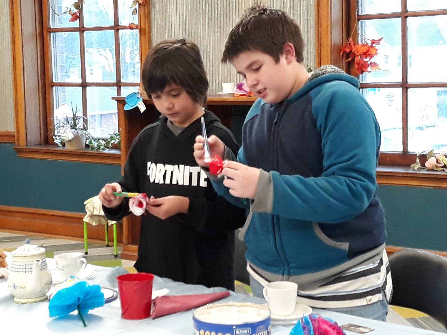 Daniel Murphy (right) and Jonathan Monferdini paint the roses red Friday, March 18, 2022, during the Mad Hatter's Tea Party at the Streator Public Library.