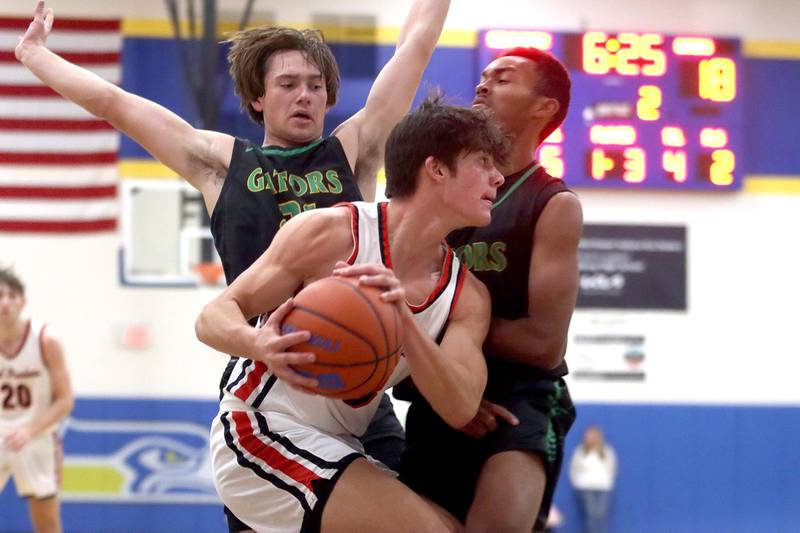 Crystal Lake South’s Cooper LePage, left, and Josh Washington, right, keep close tabs on  Huntley’s  Ty Goodrich, center, during the title game of the Johnsburg Thanksgiving tournament in boys basketball on Friday.