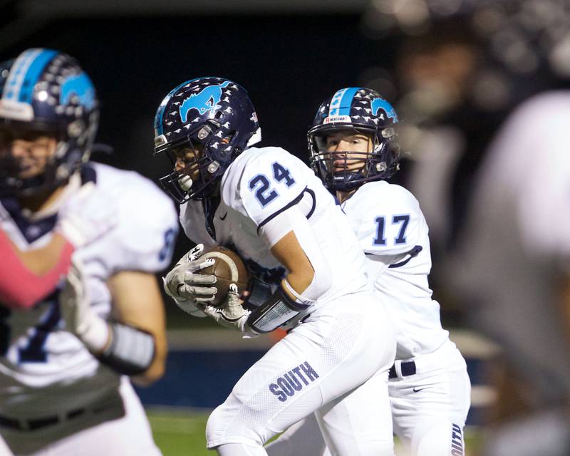 Downers Grove South's Aidan Kanazawa hands the ball off to Joseph Vleyra on Friday, Oct.25,2024 in Addison.