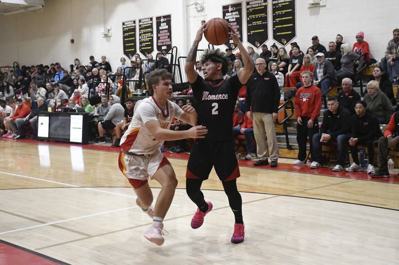 Momence's Erick Castillo looks for an open Momence player while guarded by St. Anne's Grant Pomaranski during St. Anne's 61-46 victory over Momence on Tuesday December 9, 2025.