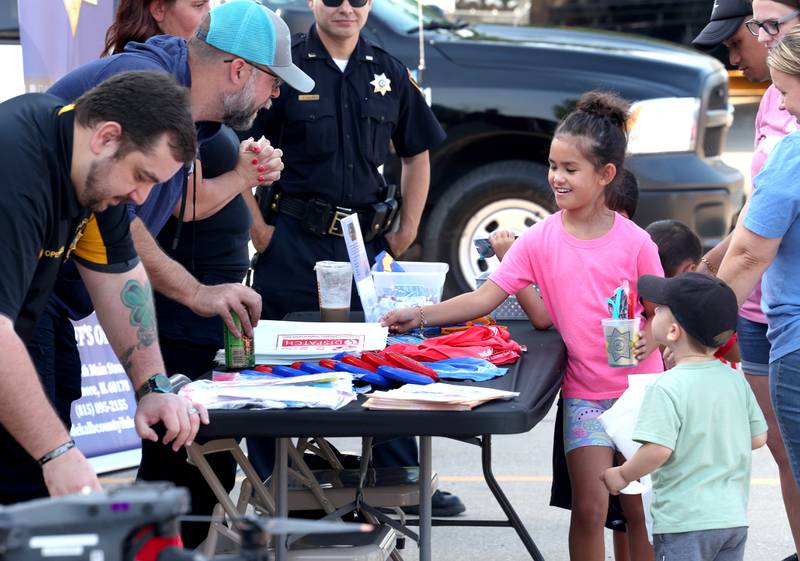Visitors pick up some freebies Tuesday, Aug. 5, 2025, at the DeKalb County Sheriff’s Department area during National Night Out in the Hy-Vee parking lot in Sycamore.